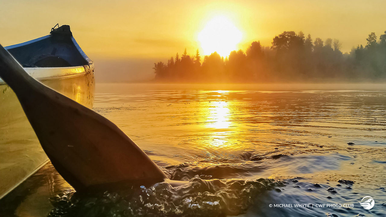 canoe on lake during sunset